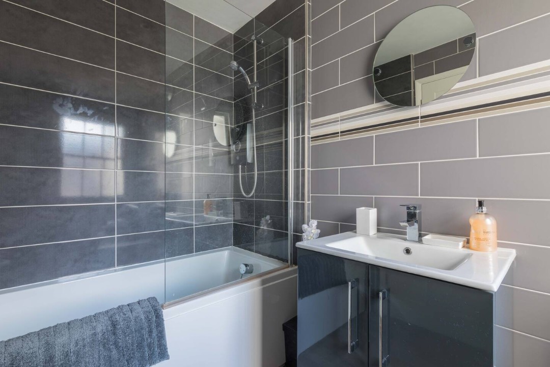 Downstairs bathroom with bath over shower, basin and WC - The Old Bakery
